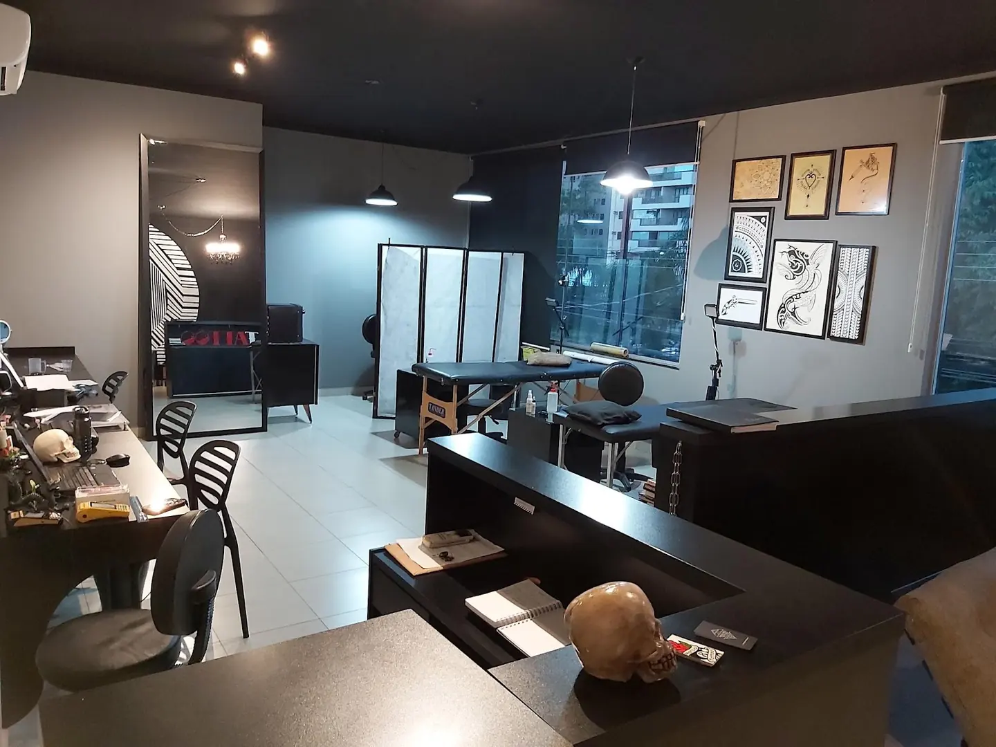 Recepção do estúdio Márcio Tattoo, com balcão, sofá e as macas ao fundo